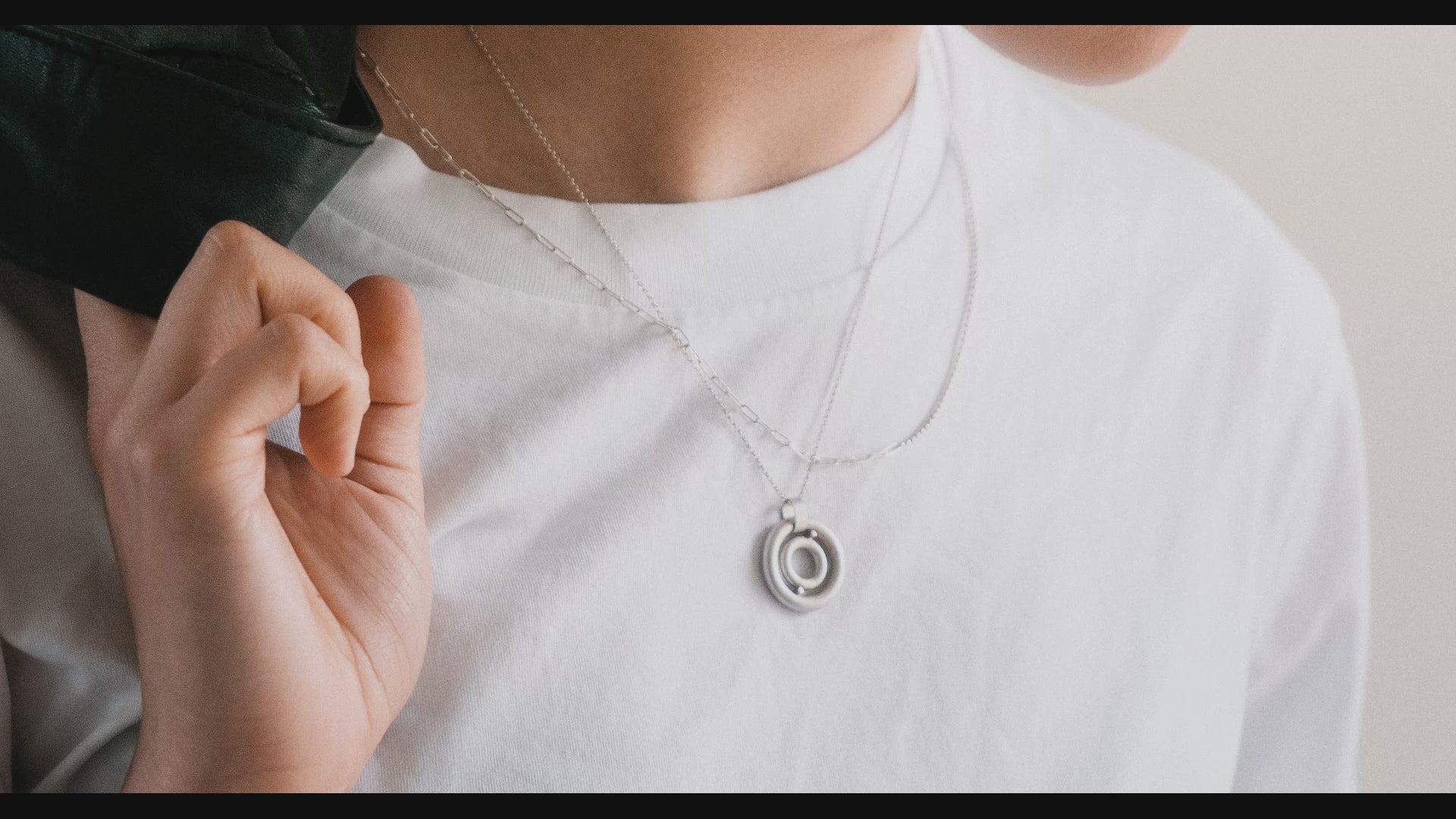 Load video: model wearing a white tshirt silver compass charm necklace staced with a silver small chain. Panning upward across their ears with silver chunky chain earrings in two lobe piercings