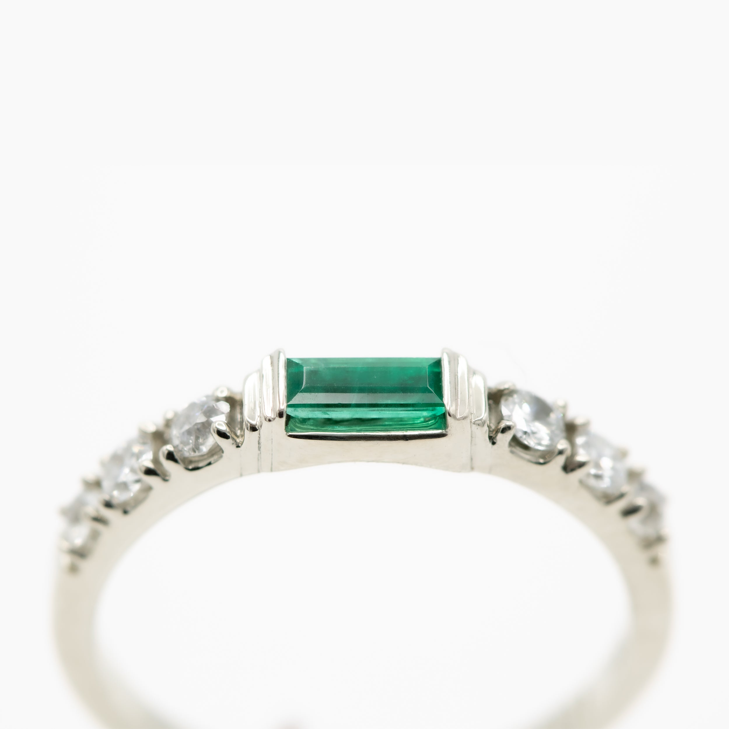 Ring with emerald and diamonds on a white background