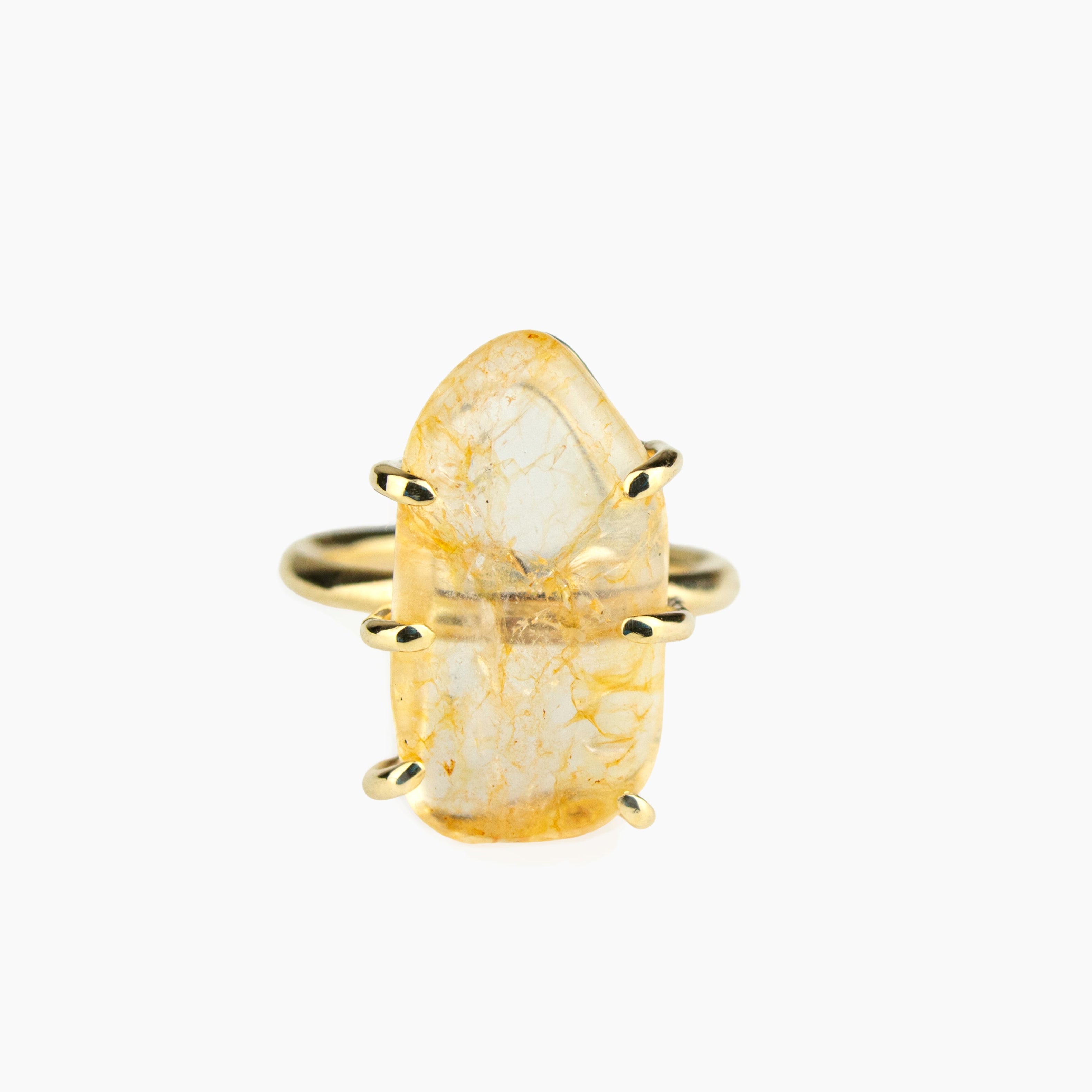 Gold ring with a large, textured stone on a white background