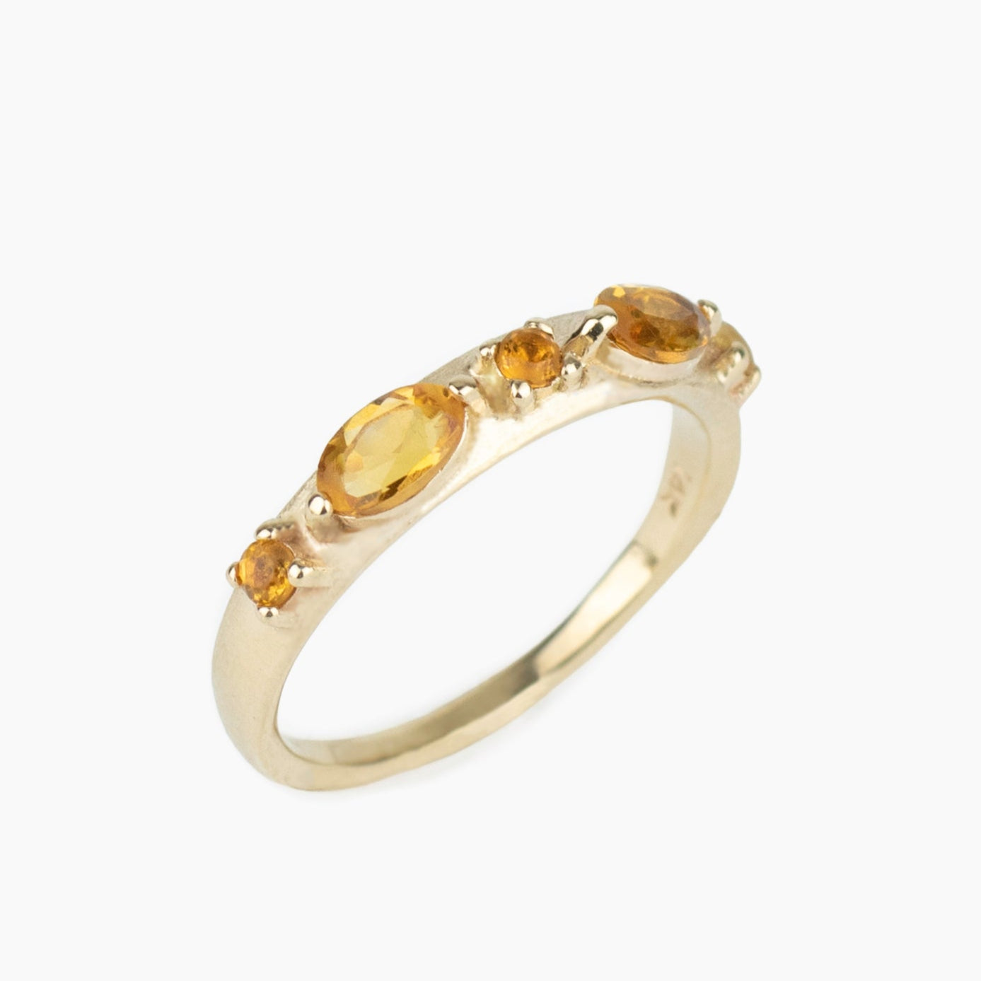 Gold ring with embedded yellow citrine gemstones on a white background
