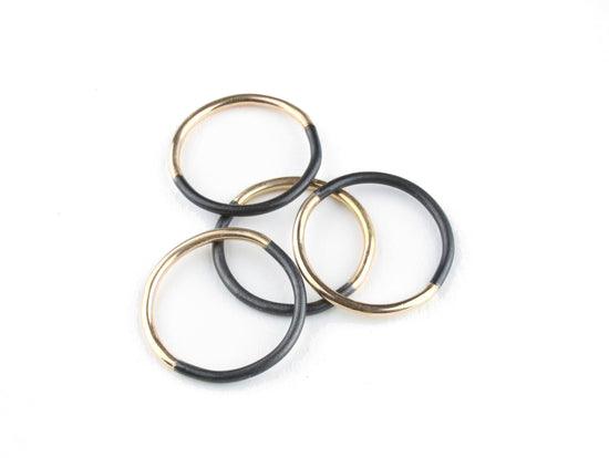 four half gold and black thin metal rings lay in a stack