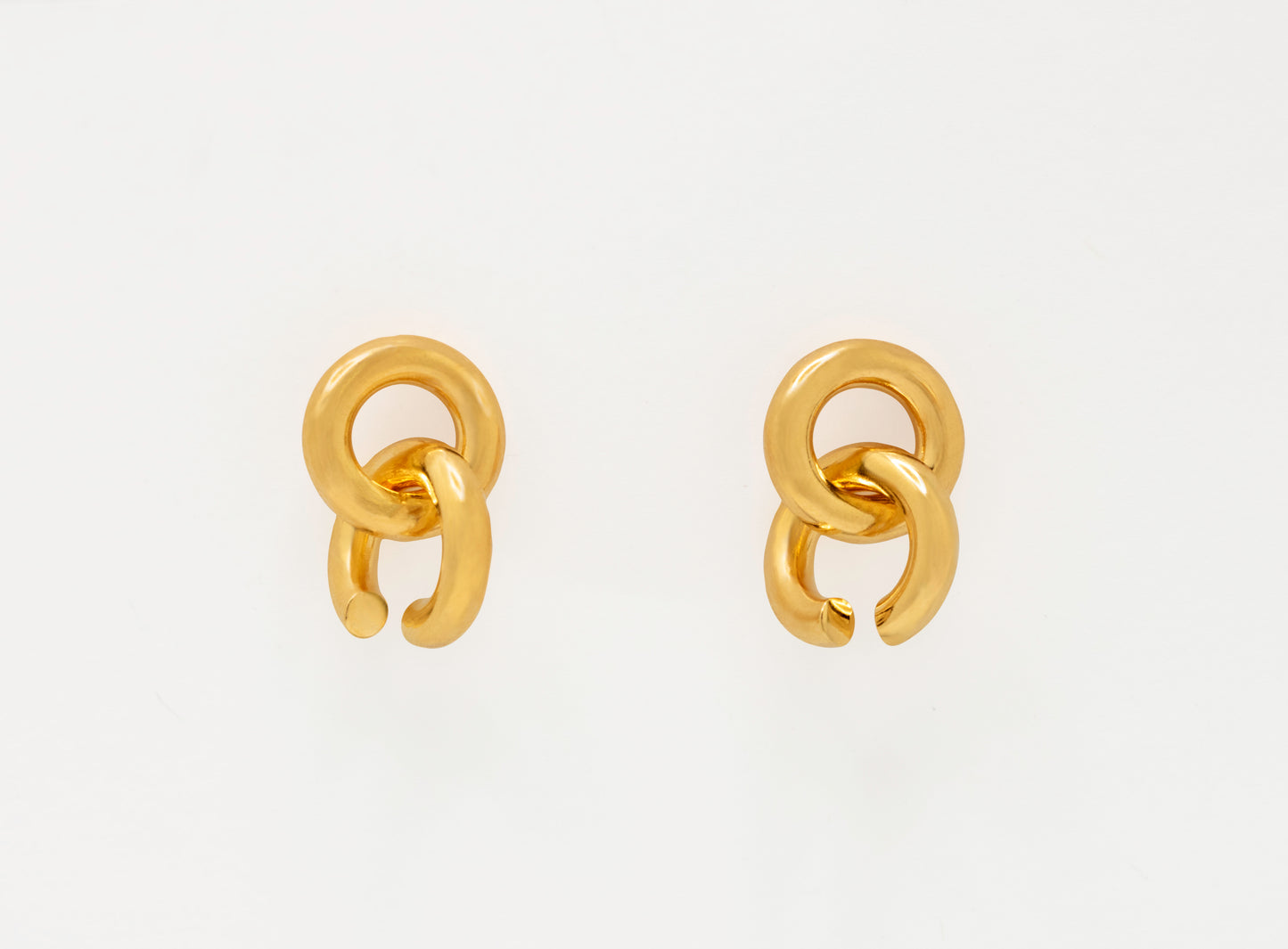 Pair of asymmetrical gold chain earrings on a white background